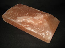 ピンク岩塩 割肌。黒い表面に置かれたピンク色の塩。